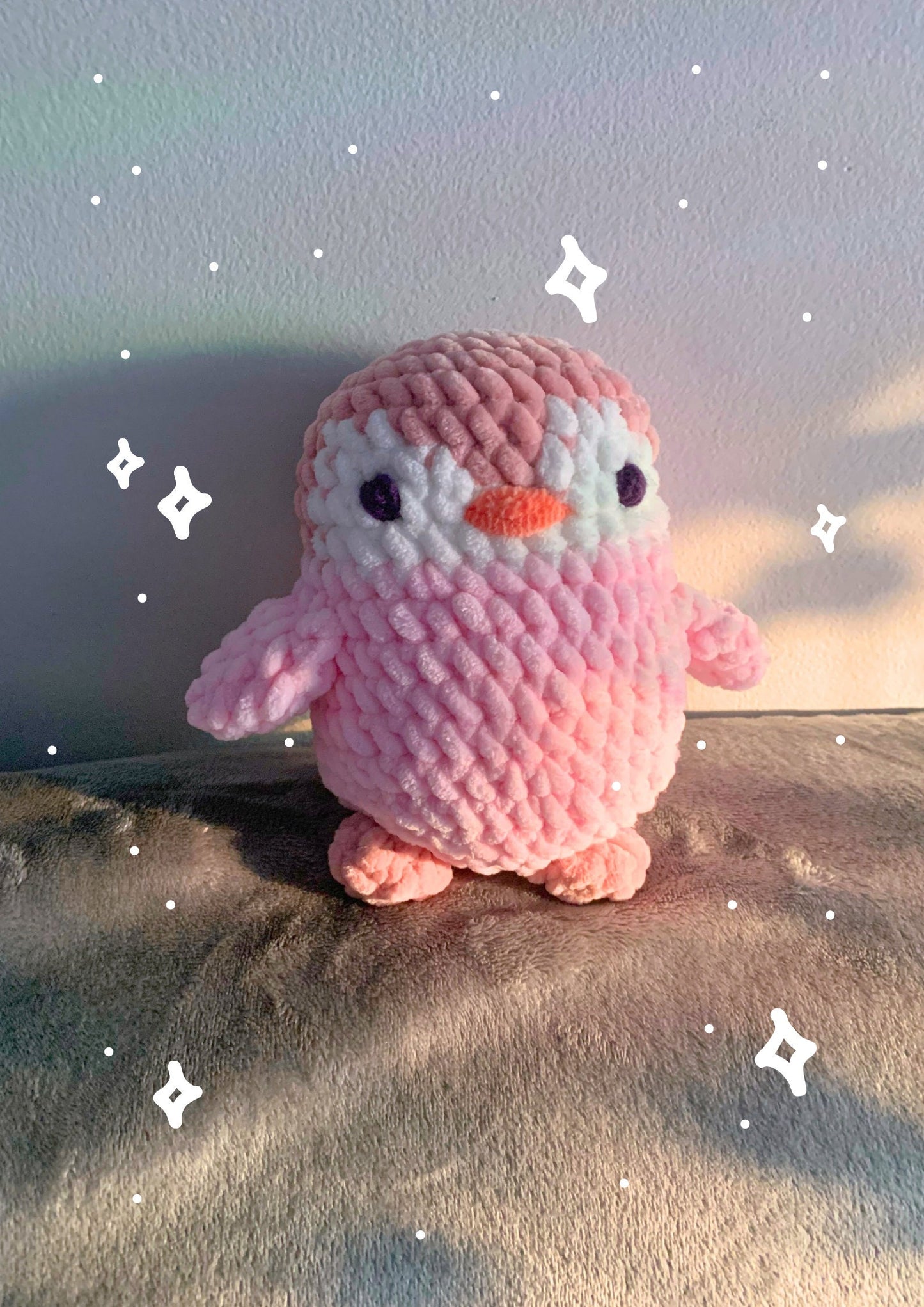 A pink crochet penguin plushie from the front.