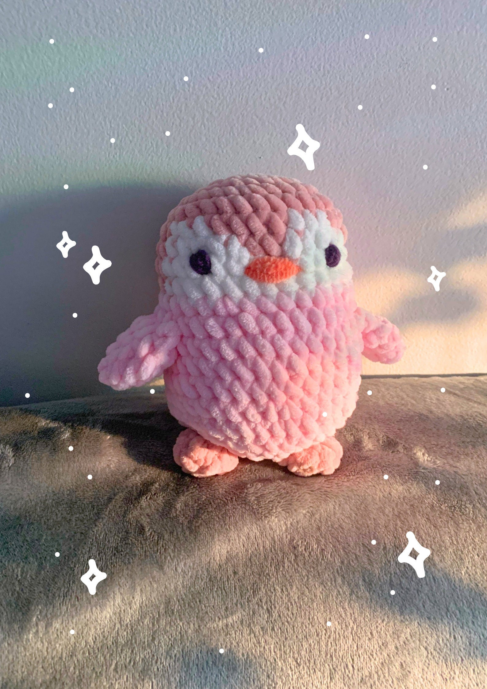 A pink crochet penguin plushie from the front.