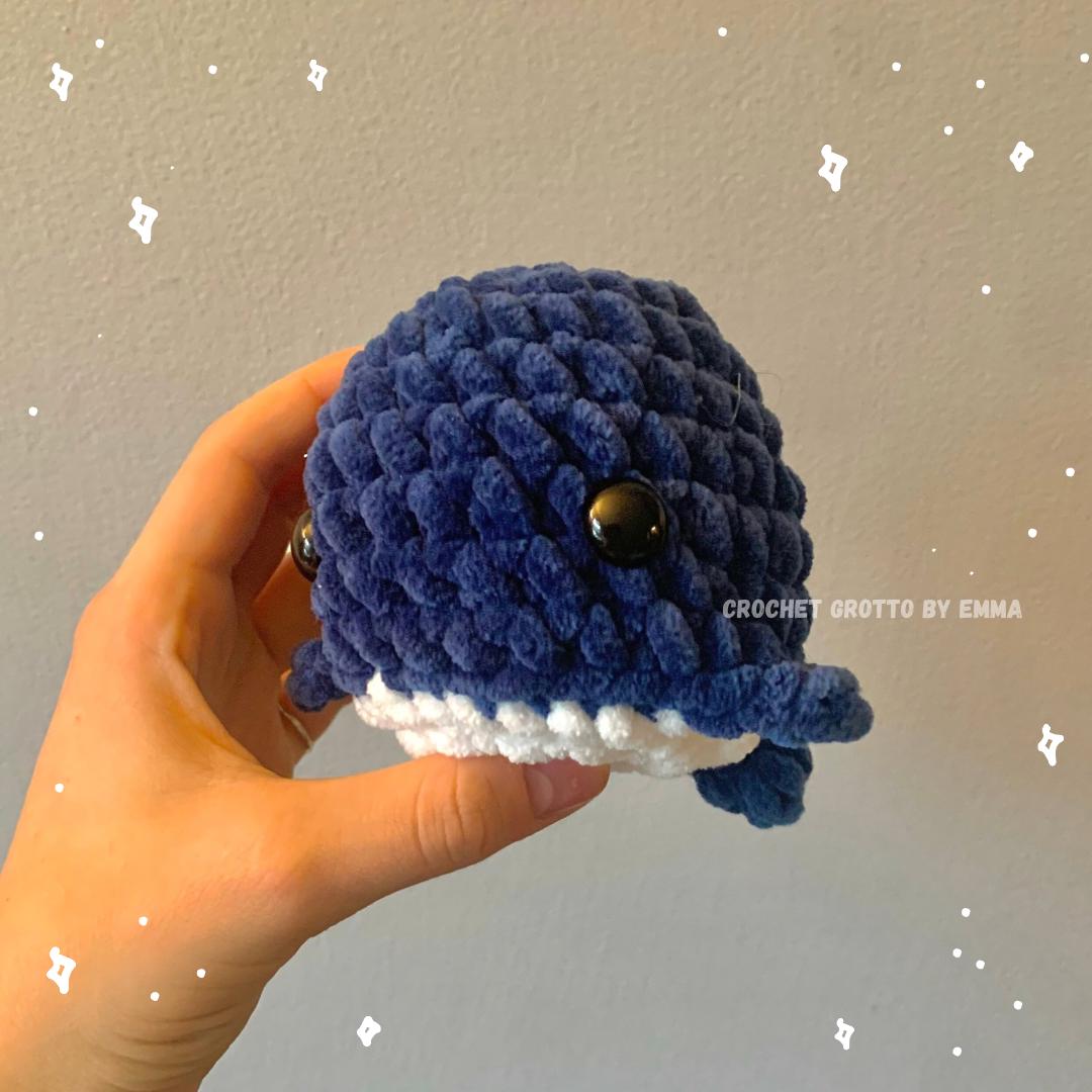 A crochet chubby whale plushie (in dark blue) showing the left side/front angle.