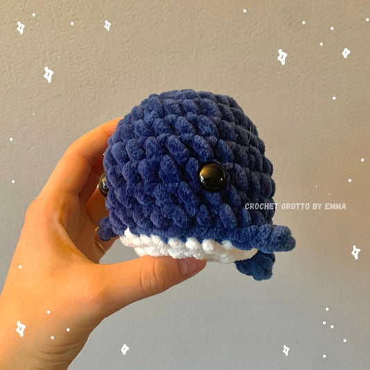 A crochet chubby whale plushie (in dark blue) showing the left side/front angle.