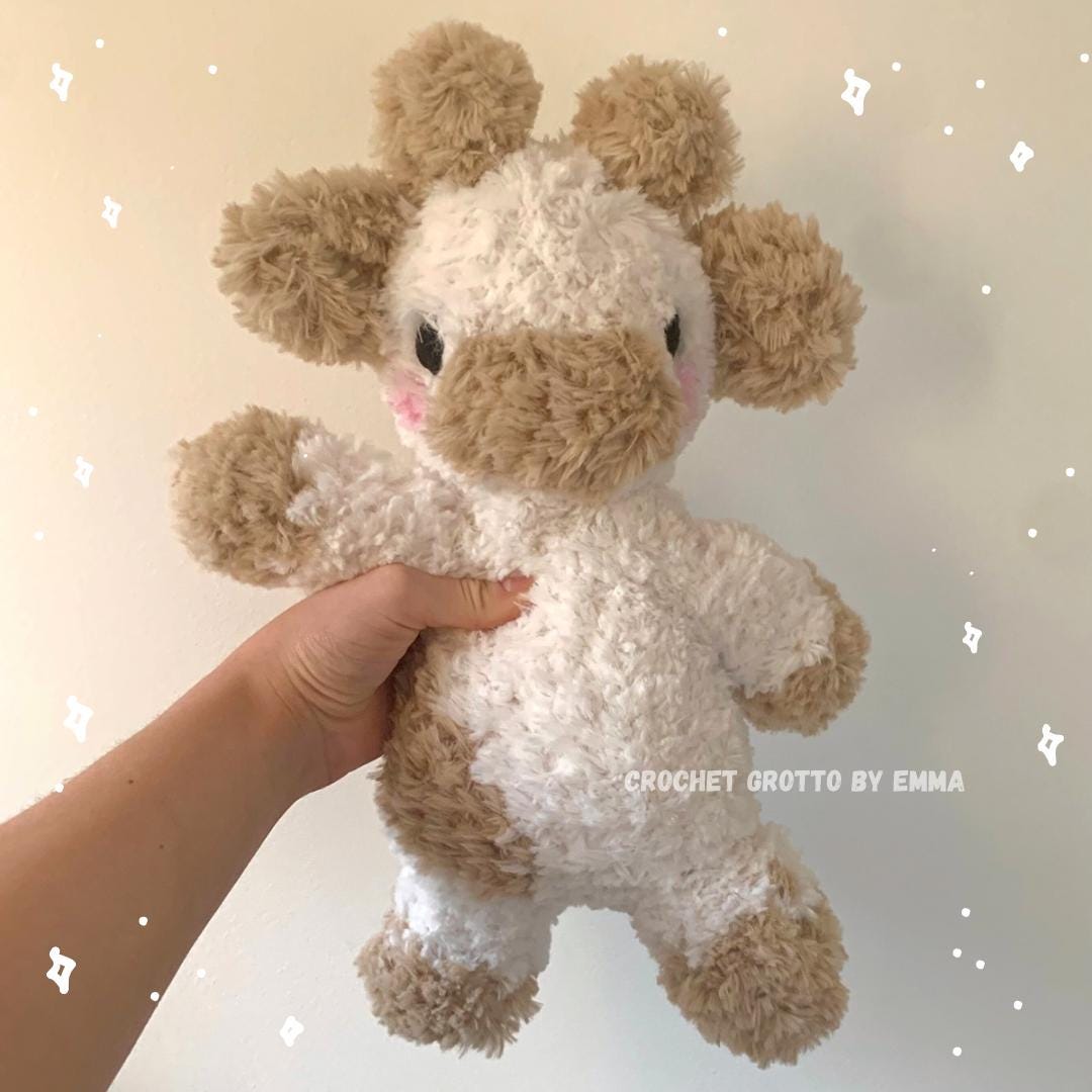 A fluffy weighted cow crochet plushie, pictured from the front.
