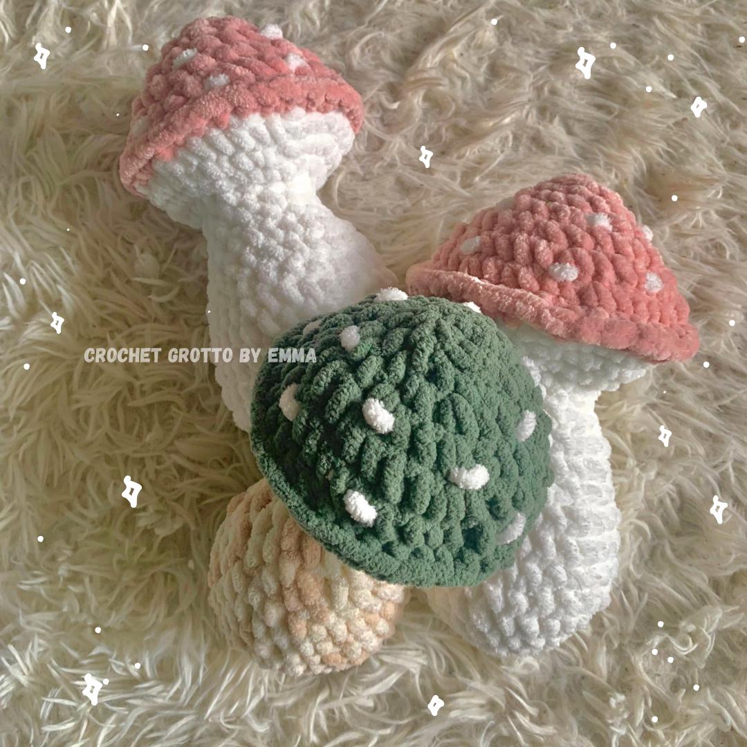 Pink and green mushroom crochet plushies/cushions, photographed on a white shag background.
