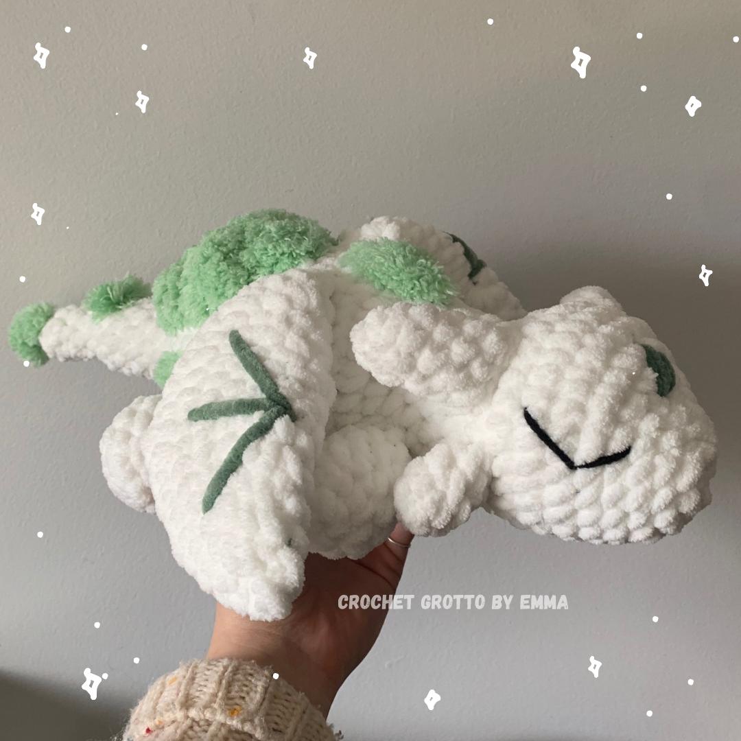 A cute white dragon with green moss patches on its back.